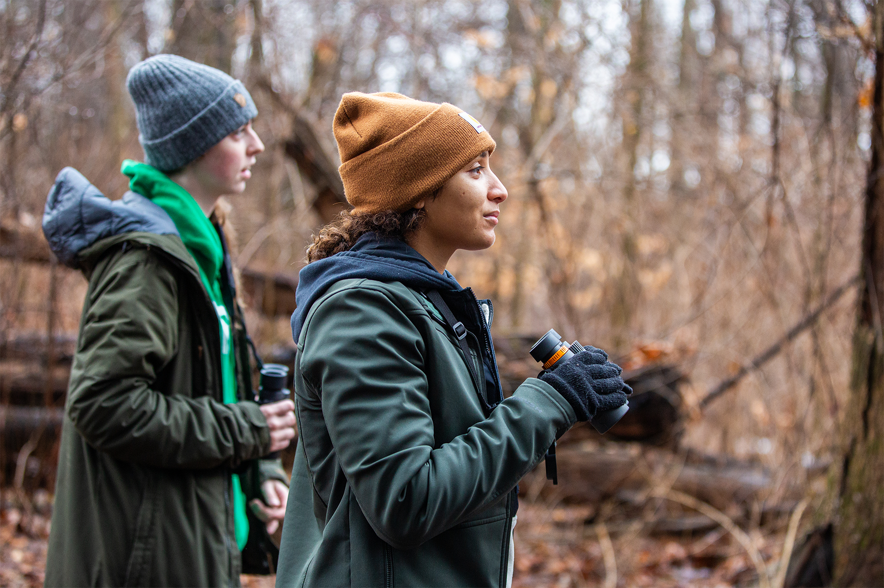 A student in the forest during a class, holding binoculars