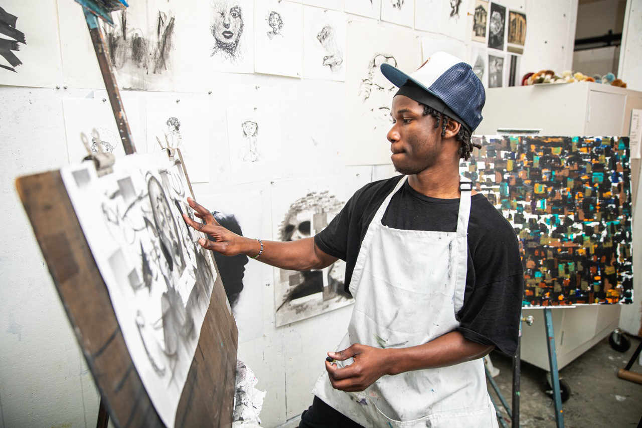 Art student creating a charcoal drawing on an easel in a studio