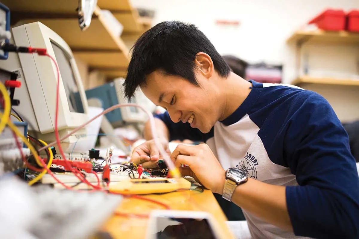 Student assembling an electronics project at a makerspace workbench.