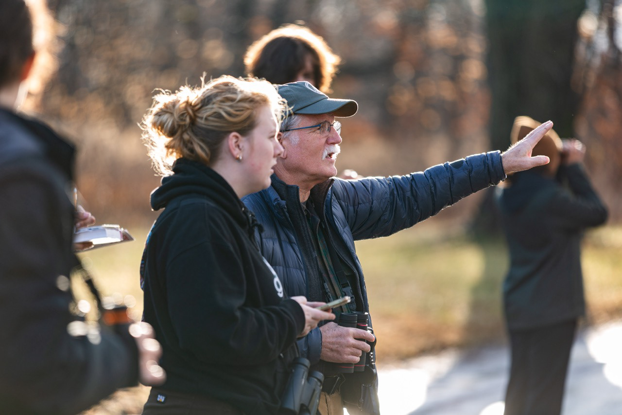 Instructor pointing out wildlife to students during an outdoor field study.